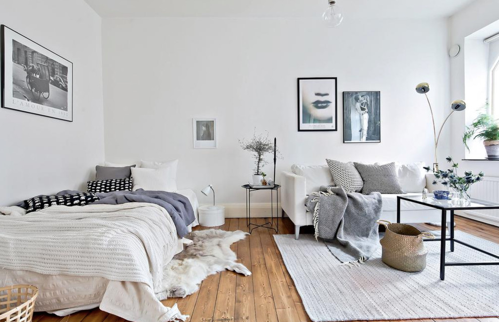 Scandinavian bedroom in Gothenburg with white walls and medium hardwood floors.