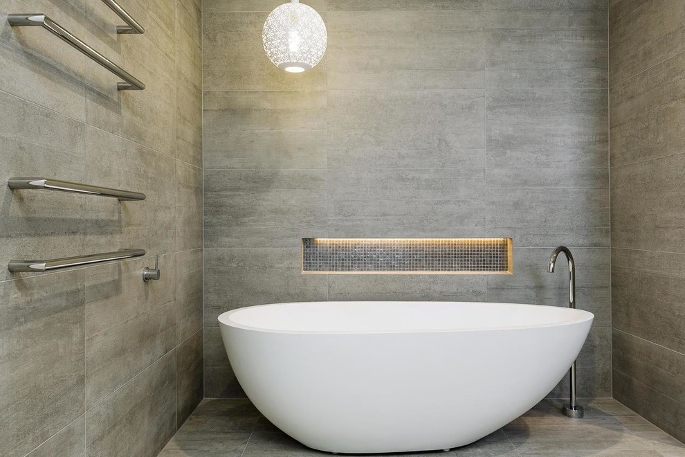 This is an example of a large transitional master bathroom in Sydney with a freestanding tub, a double shower, a one-piece toilet, gray tile, porcelain tile, grey walls, porcelain floors, engineered quartz benchtops, grey floor and a hinged shower door.
