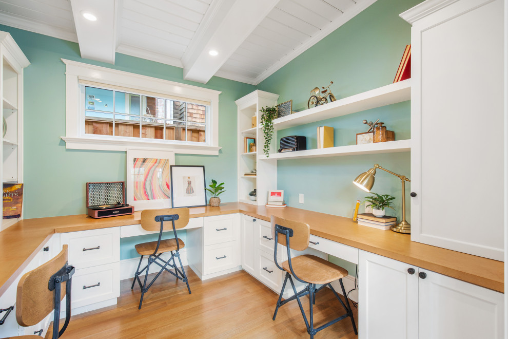 Transitional gender-neutral kids' study room in San Francisco with green walls, light hardwood floors and exposed beam.