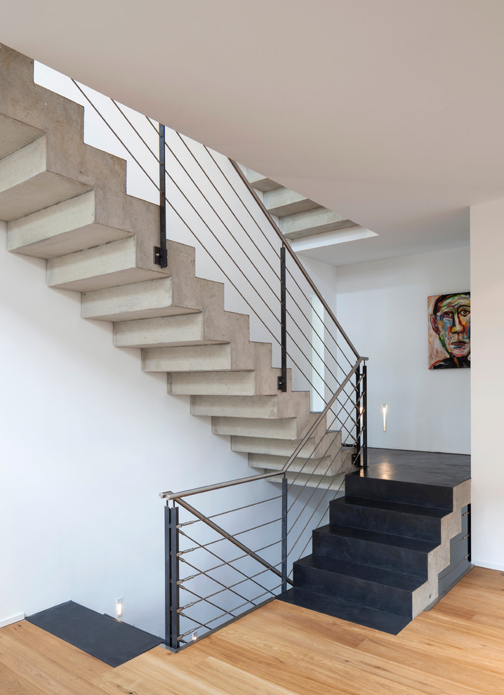 This is an example of a mid-sized contemporary concrete straight staircase in Cologne with concrete risers and metal railing.