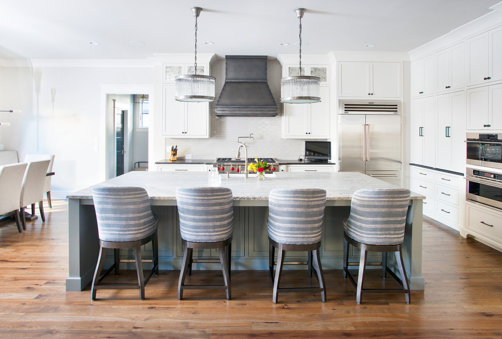 Transitional eat-in kitchen in Nashville with shaker cabinets, white cabinets, white splashback, stainless steel appliances, medium hardwood floors, with island and black benchtop.