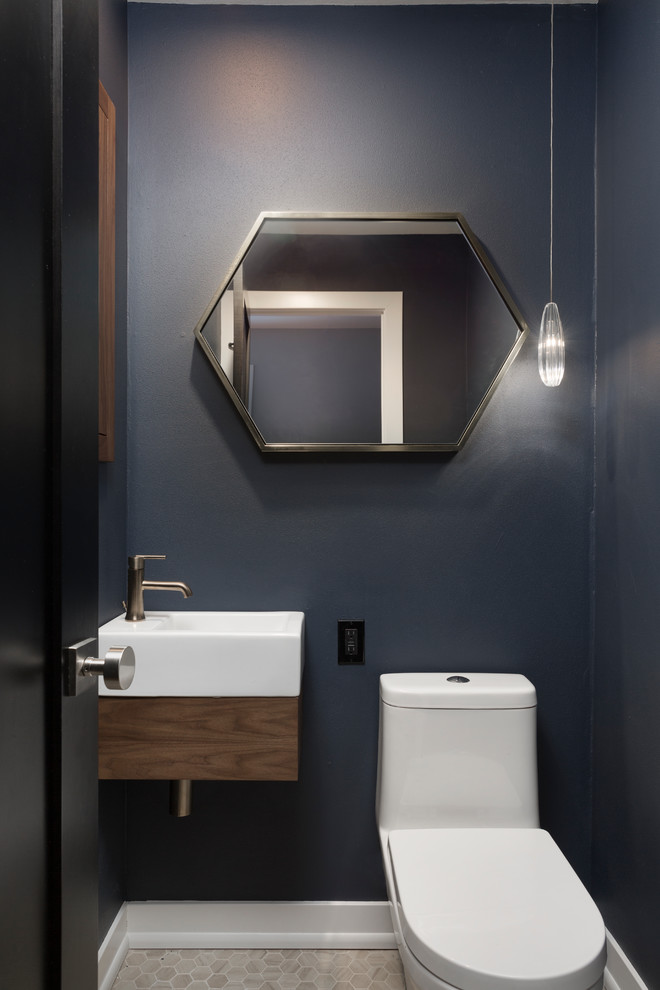 Small contemporary powder room in Milwaukee with flat-panel cabinets, brown cabinets, a one-piece toilet, blue walls, porcelain floors, a wall-mount sink and beige floor.