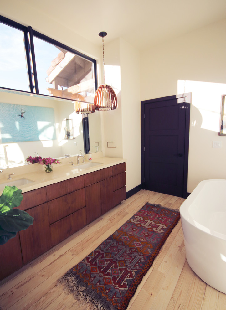 Design ideas for a large country master bathroom in Los Angeles with flat-panel cabinets, brown cabinets, a freestanding tub, a corner shower, a one-piece toilet, white walls, light hardwood floors, an undermount sink, engineered quartz benchtops, beige floor and a hinged shower door.
