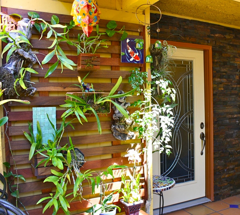 Inspiration for a small tropical courtyard patio in Los Angeles with a vertical garden, tile and a roof extension.