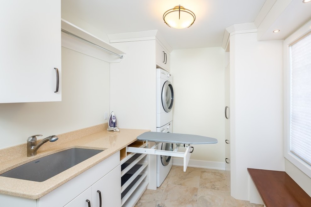 Inspiration for a small transitional single-wall dedicated laundry room in Toronto with an undermount sink, flat-panel cabinets, white cabinets, quartz benchtops, white walls, marble floors and a stacked washer and dryer.