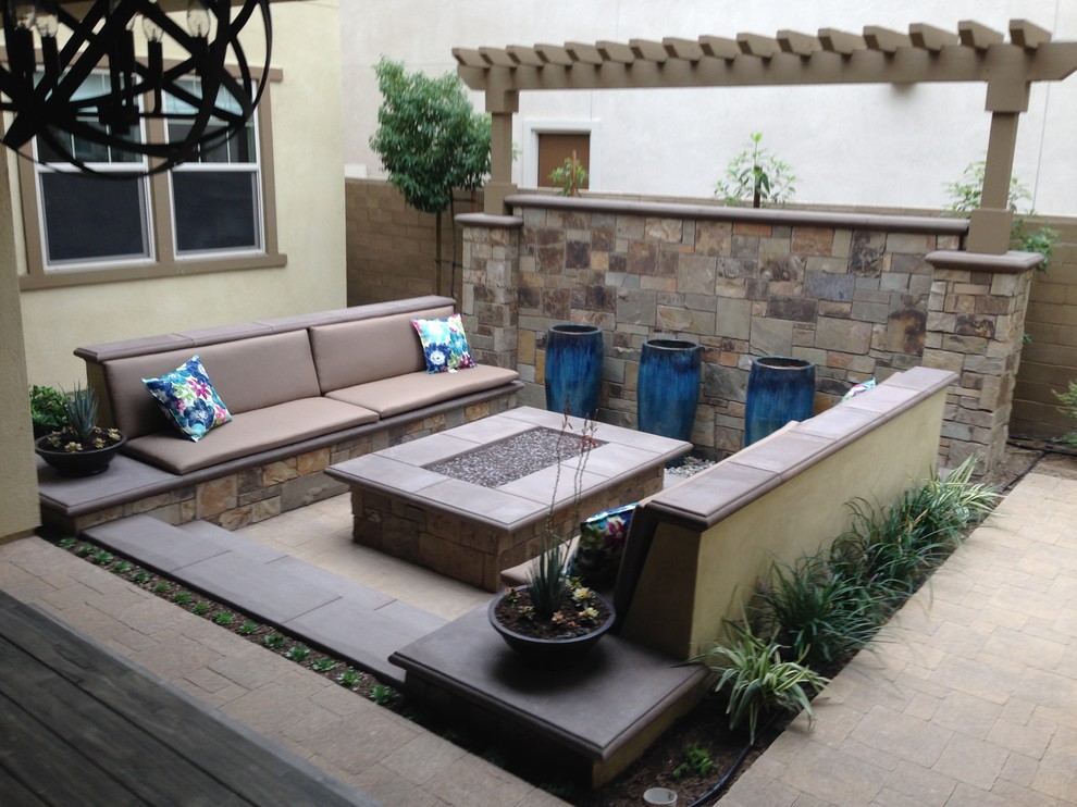 Inspiration for a mid-sized transitional backyard stone patio fountain remodel in Orange County with a roof extension