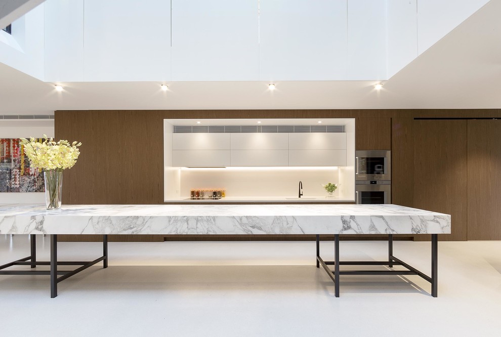 This is an example of a large contemporary single-wall open plan kitchen in Melbourne with flat-panel cabinets, brown cabinets, marble benchtops, white splashback, stainless steel appliances and with island.