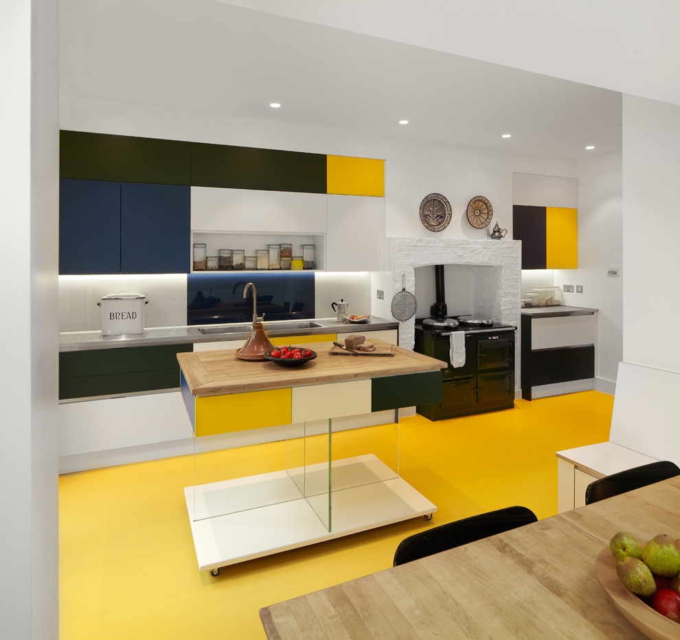 Design ideas for a mid-sized contemporary u-shaped open plan kitchen in London with a single-bowl sink, flat-panel cabinets, stainless steel benchtops, yellow splashback, glass sheet splashback, stainless steel appliances, linoleum floors and with island.