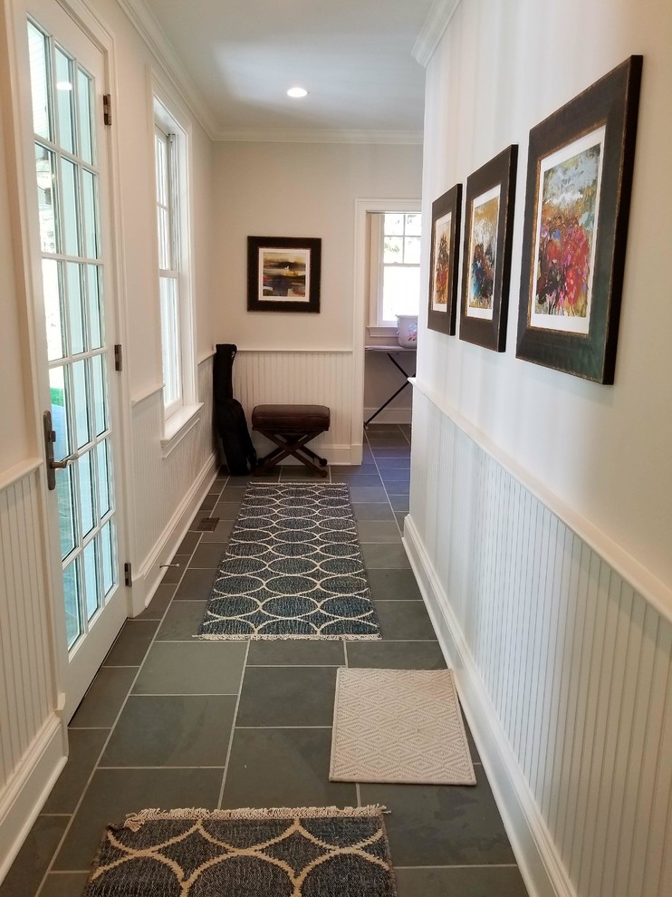 Photo of a mid-sized transitional hallway in New York with beige walls, slate floors and grey floor.