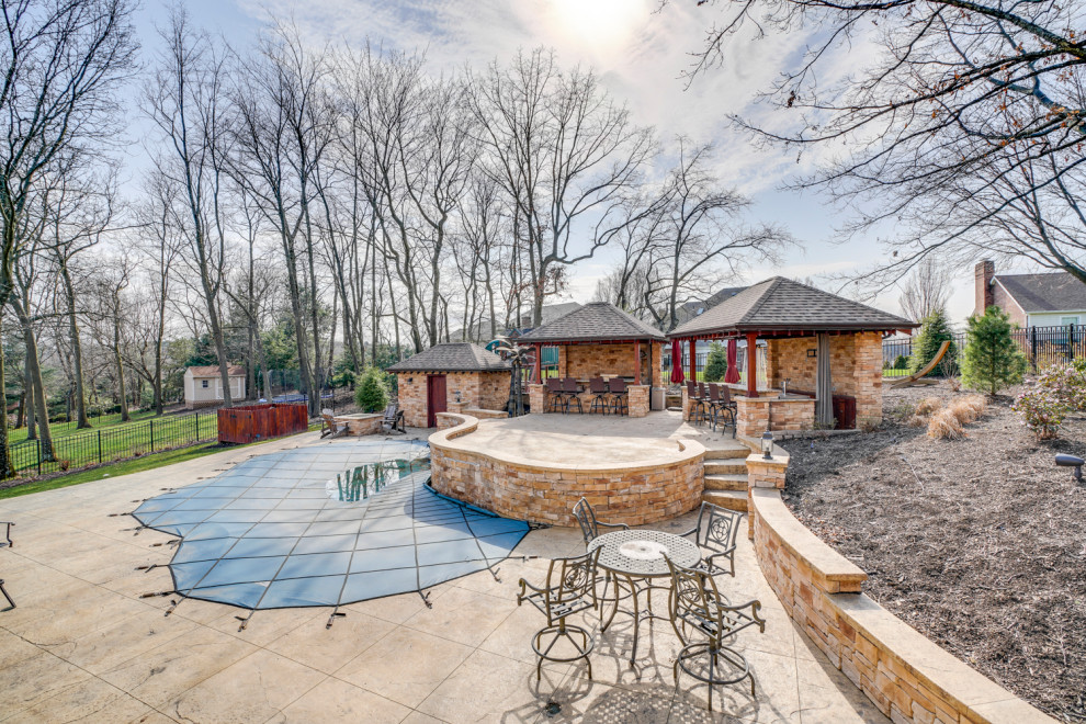 This is an example of a large arts and crafts backyard patio in Other with an outdoor kitchen, concrete pavers and a roof extension.