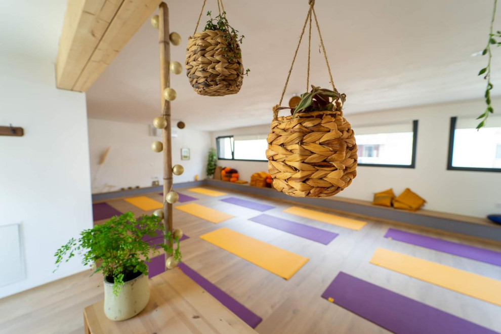 Mittelgroßer Yogaraum mit weißer Wandfarbe, hellem Holzboden und braunem Boden in Grenoble