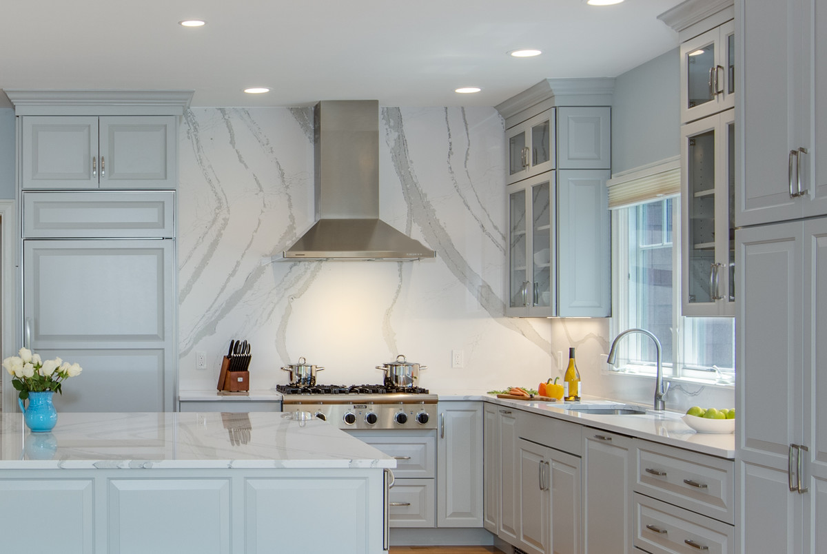 This is an example of a large transitional l-shaped open plan kitchen in Boston with an undermount sink, raised-panel cabinets, grey cabinets, quartz benchtops, stone slab splashback, panelled appliances, medium hardwood floors and with island.