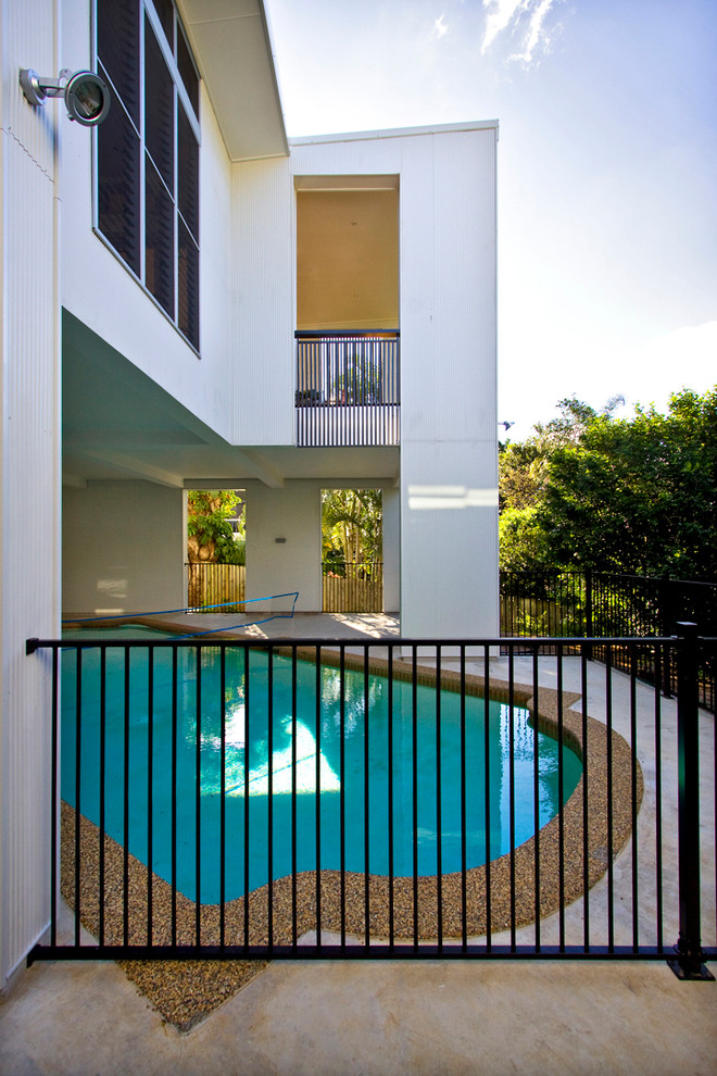 Large modern backyard custom-shaped pool in Brisbane with concrete slab.