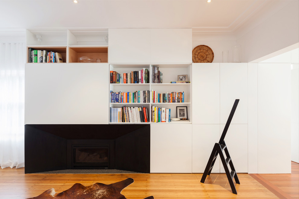 This is an example of a contemporary living room in Sydney with white walls, light hardwood floors, a standard fireplace and a plaster fireplace surround.