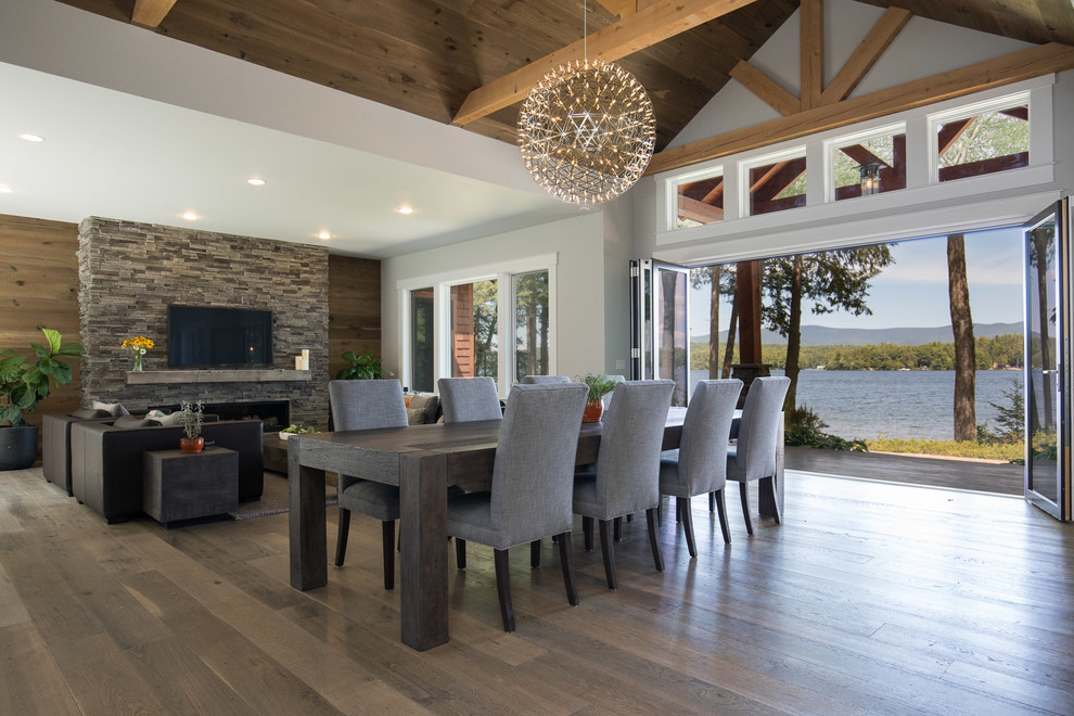 Contemporary open plan dining in Boston with white walls, medium hardwood floors, a ribbon fireplace, a stone fireplace surround and brown floor.