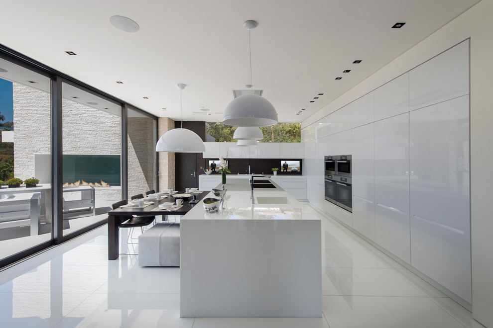 Photo of an expansive modern l-shaped eat-in kitchen in Los Angeles with flat-panel cabinets, white cabinets, stainless steel appliances, with island, white floor, white benchtop and recessed.