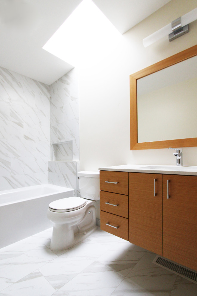 Mid-sized transitional 3/4 black and white tile and porcelain tile porcelain tile, white floor and single-sink alcove bathtub photo with flat-panel cabinets, light wood cabinets, a two-piece toilet, white walls, an undermount sink, quartz countertops, white countertops, a niche and a floating vanity