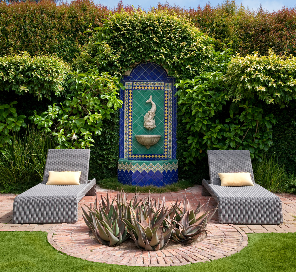 Mediterranean patio in Santa Barbara with a water feature, brick pavers and no cover.