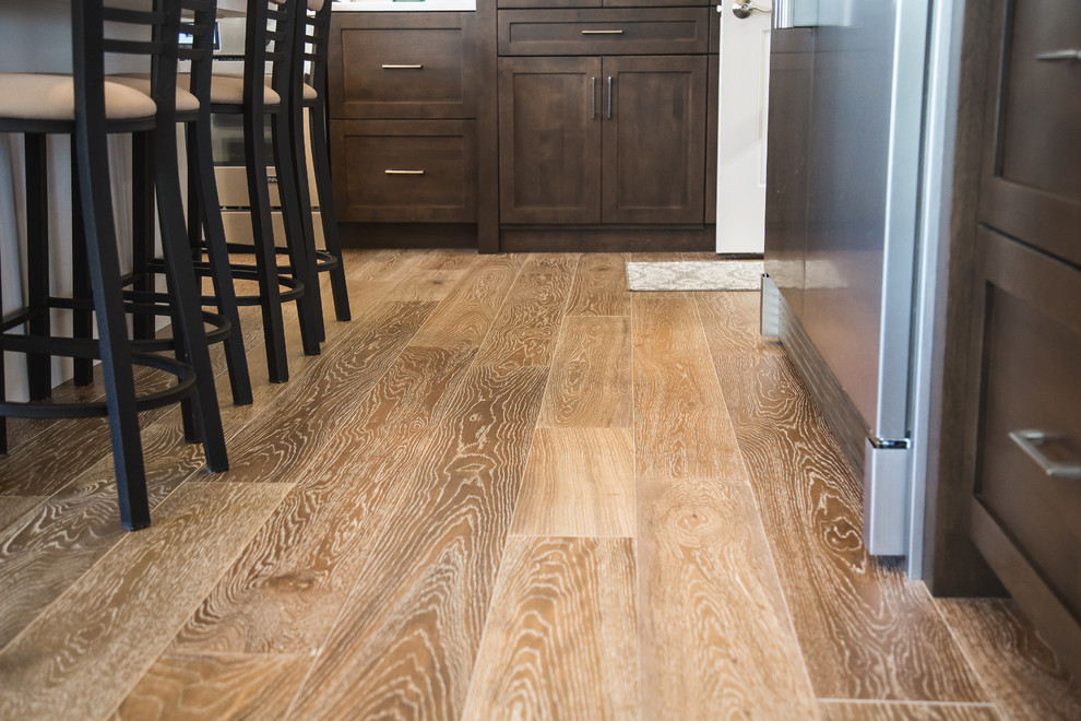 Kitchen - transitional brown floor and medium tone wood floor kitchen idea with recessed-panel cabinets, dark wood cabinets, white backsplash, stainless steel appliances and marble backsplash