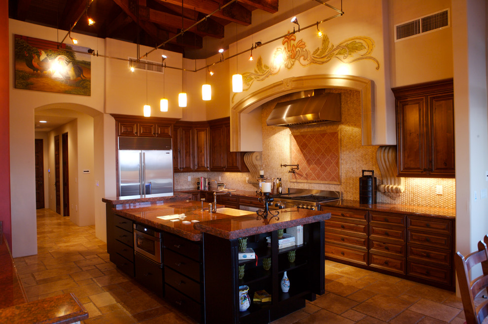 This is an example of a large contemporary l-shaped eat-in kitchen in Phoenix with a farmhouse sink, raised-panel cabinets, medium wood cabinets, granite benchtops, beige splashback, mosaic tile splashback, stainless steel appliances, travertine floors, with island and beige floor.