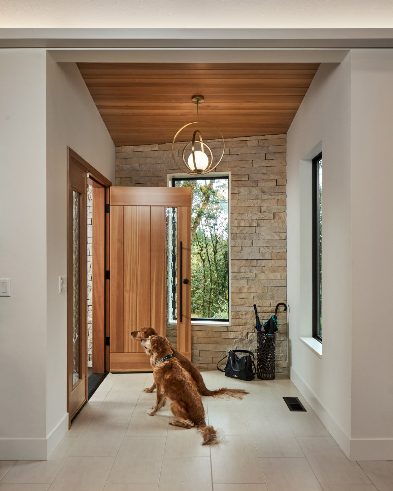 Réalisation d'une porte d'entrée design avec un sol en carrelage de porcelaine, une porte simple, une porte en bois brun, un sol beige, un plafond en bois et un mur en parement de brique.