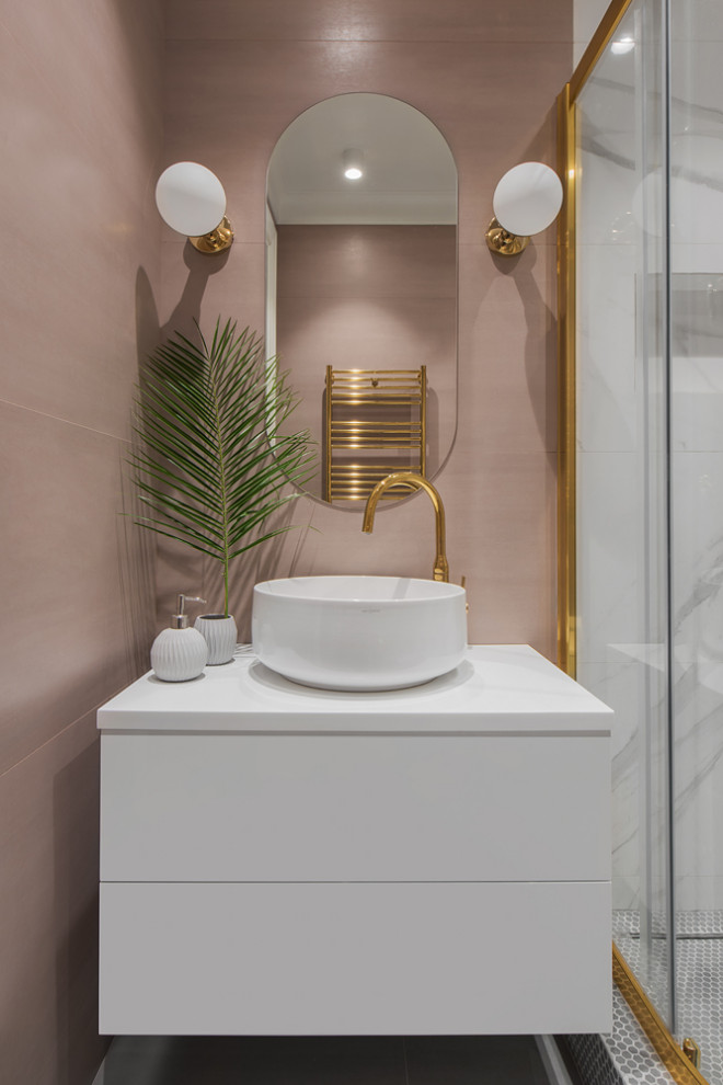 Mid-sized transitional 3/4 bathroom in Moscow with flat-panel cabinets, white cabinets, a corner shower, a wall-mount toilet, pink tile, porcelain tile, pink walls, porcelain floors, a drop-in sink, solid surface benchtops, grey floor, a sliding shower screen and white benchtops.