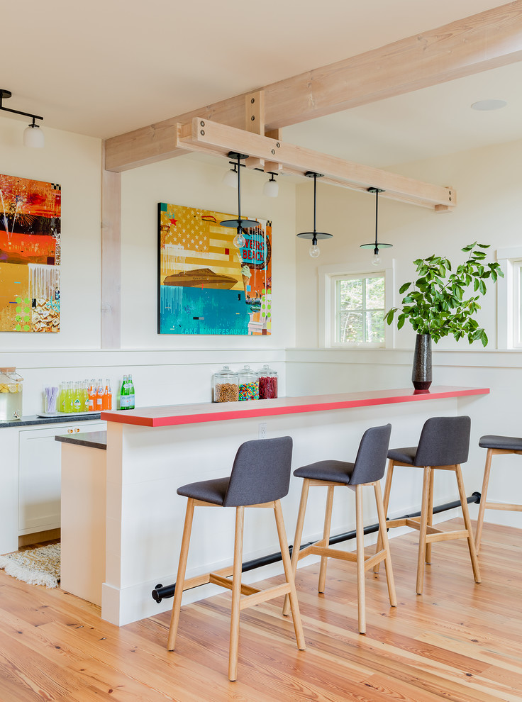 This is an example of a contemporary kitchen in Portland Maine with white cabinets, medium hardwood floors, a peninsula, brown floor and multi-coloured benchtop.