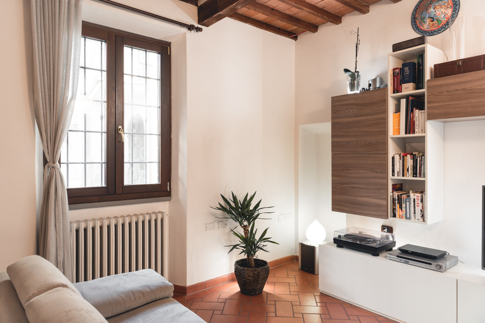 This is an example of a small contemporary enclosed living room in Florence with white walls, terra-cotta floors, a freestanding tv, orange floor and exposed beam.