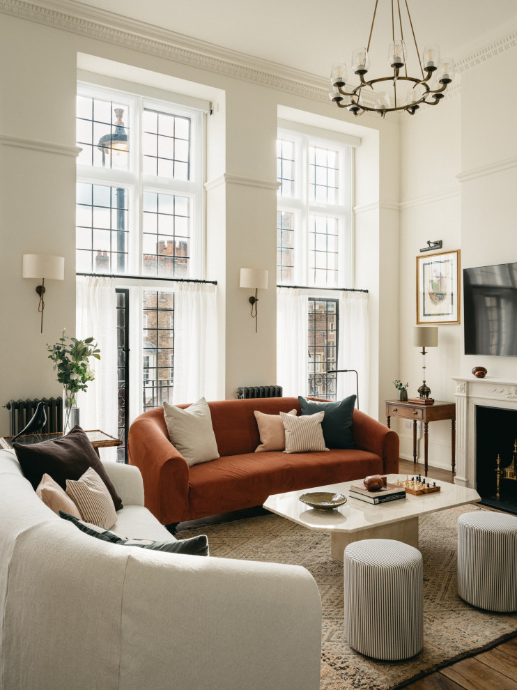This is an example of a traditional living room in London with white walls, dark hardwood flooring, a standard fireplace, a wall mounted tv and brown floors.