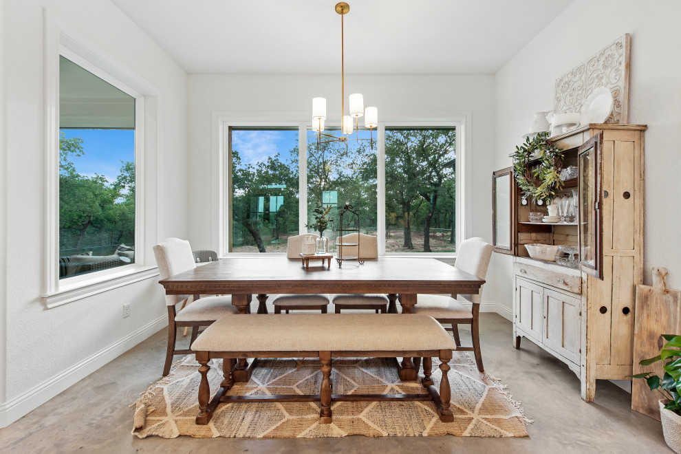 Esempio di una sala da pranzo aperta verso la cucina country di medie dimensioni con pareti bianche, pavimento in cemento, pavimento beige e travi a vista