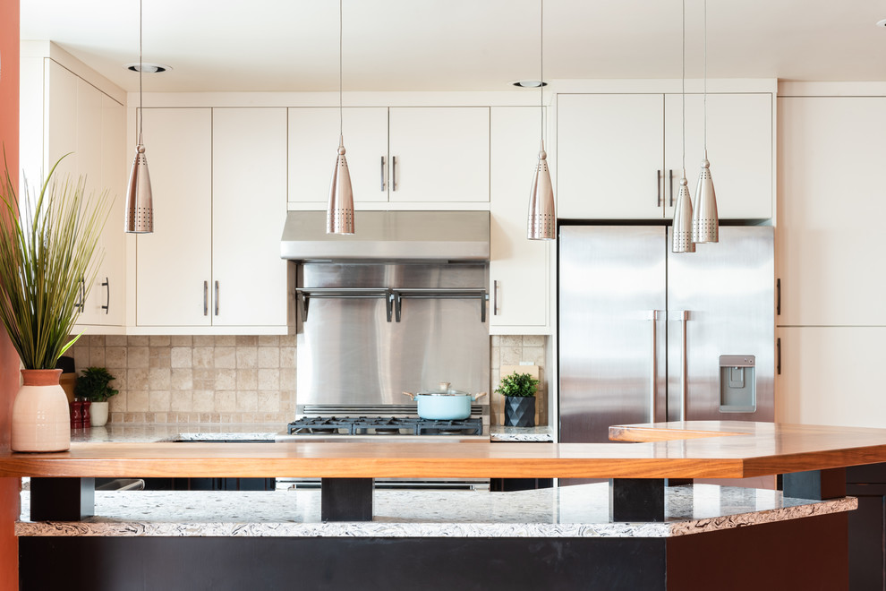 Mid-sized transitional u-shaped medium tone wood floor and brown floor eat-in kitchen photo with an undermount sink, shaker cabinets, distressed cabinets, quartz countertops, white backsplash, travertine backsplash, stainless steel appliances, a peninsula and multicolored countertops