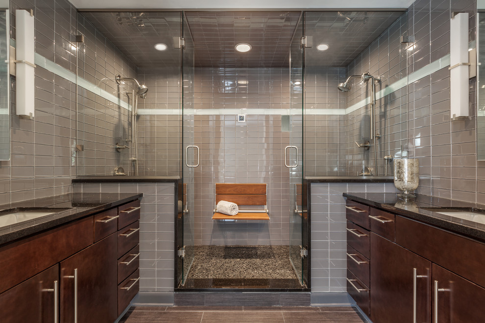 Photo of a transitional bathroom in Other with flat-panel cabinets, dark wood cabinets, a double shower, gray tile, grey walls, an undermount sink, grey floor and a hinged shower door.