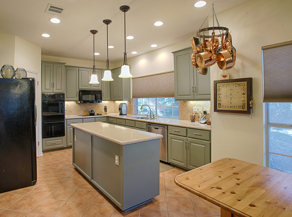 Mid-sized traditional u-shaped eat-in kitchen in Austin with raised-panel cabinets, green cabinets, beige splashback, ceramic splashback, black appliances, ceramic floors and with island.