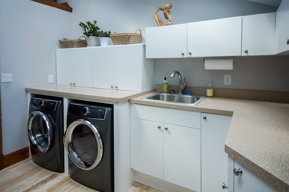 This is an example of a large transitional l-shaped dedicated laundry room in Cincinnati with flat-panel cabinets, white cabinets, laminate benchtops, white walls, ceramic floors, a side-by-side washer and dryer, beige floor, a drop-in sink and beige benchtop.