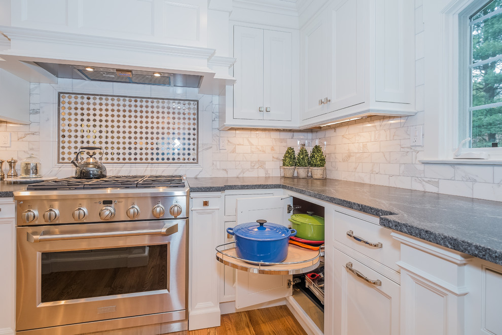 Photo of a large traditional l-shaped eat-in kitchen in New York with an undermount sink, beaded inset cabinets, white cabinets, granite benchtops, white splashback, stone tile splashback, stainless steel appliances, medium hardwood floors and with island.