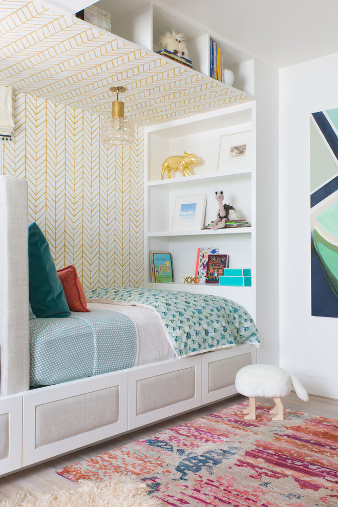 This is an example of a transitional gender-neutral kids' bedroom in San Francisco with multi-coloured walls and light hardwood floors.