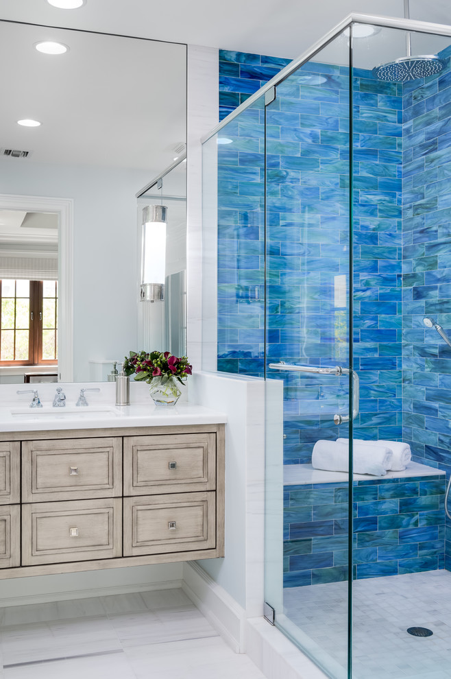 Inspiration for a transitional 3/4 bathroom in Other with shaker cabinets, light wood cabinets, a corner shower, blue tile, subway tile, white walls, an undermount sink, white floor, a hinged shower door and white benchtops.