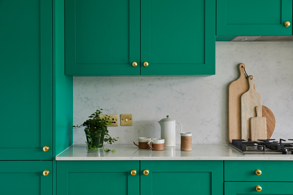 ロンドンにあるおしゃれなアイランドキッチン (シェーカースタイル扉のキャビネット、緑のキャビネット、大理石カウンター、茶色い床、白いキッチンカウンター) の写真