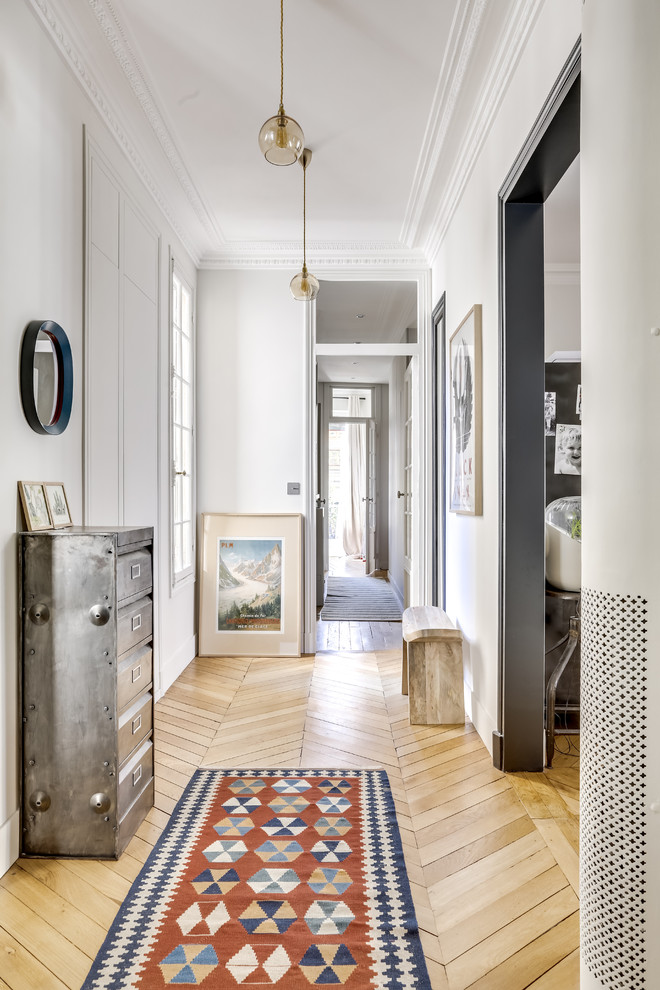 Photo of an eclectic hallway in Paris with white walls, light hardwood floors and beige floor.