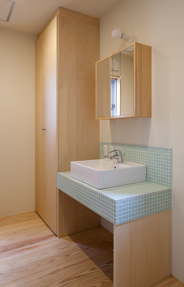 Mid-sized asian bathroom in Other with white walls, a vessel sink, blue tile, mosaic tile, light hardwood floors, tile benchtops, open cabinets, white cabinets, a one-piece toilet, blue benchtops, a single vanity and a built-in vanity.
