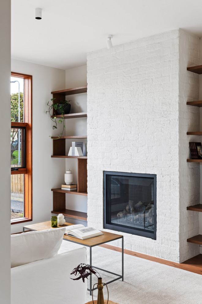 Idées déco pour un salon scandinave avec un mur blanc, un sol en bois brun, une cheminée standard et un manteau de cheminée en brique.