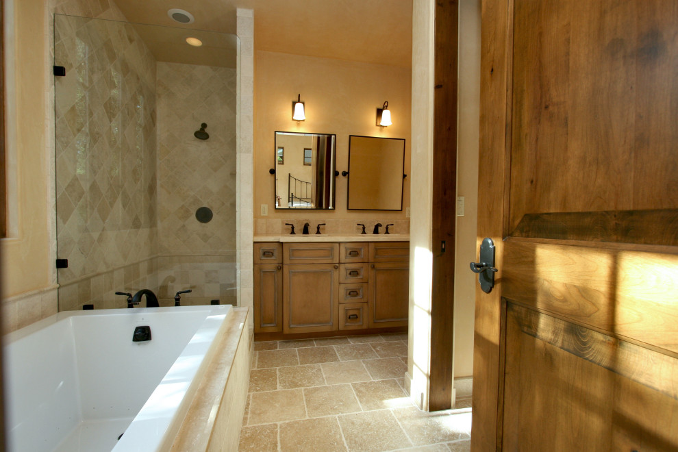 This is an example of a large mediterranean master bathroom in Other with recessed-panel cabinets, dark wood cabinets, a drop-in tub, an alcove shower, a two-piece toilet, beige tile, travertine, beige walls, travertine floors, an undermount sink, limestone benchtops, beige floor, an open shower and beige benchtops.