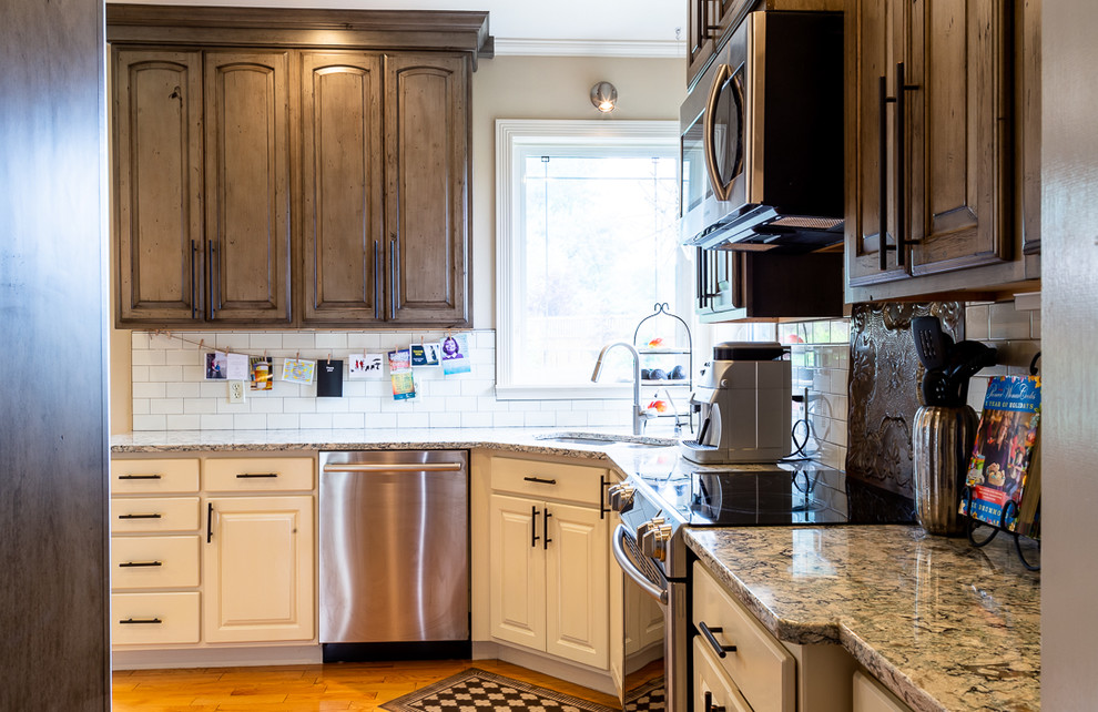 Photo of a mid-sized country kitchen in Other with an undermount sink, raised-panel cabinets, distressed cabinets, quartz benchtops, subway tile splashback, stainless steel appliances, medium hardwood floors, a peninsula, brown floor and white benchtop.