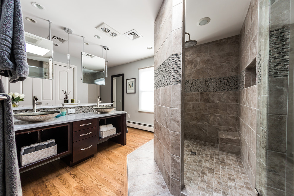 Photo of a mid-sized contemporary master bathroom in Other with a vessel sink, flat-panel cabinets, dark wood cabinets, engineered quartz benchtops, an open shower, medium hardwood floors, a one-piece toilet, gray tile, porcelain tile, grey walls, multi-coloured floor and a hinged shower door.
