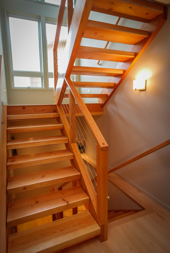 Inspiration for a mid-sized contemporary wood u-shaped staircase in Seattle with open risers and cable railing.