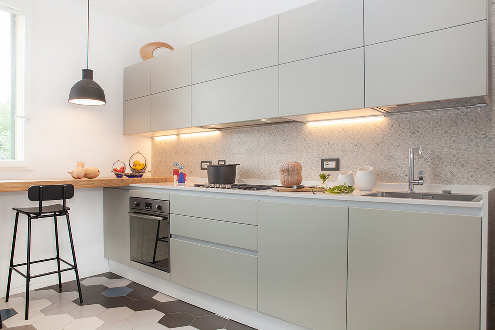 Design ideas for a contemporary single-wall kitchen in Bologna with a drop-in sink, flat-panel cabinets, white cabinets, solid surface benchtops, multi-coloured splashback, ceramic splashback, stainless steel appliances and ceramic floors.
