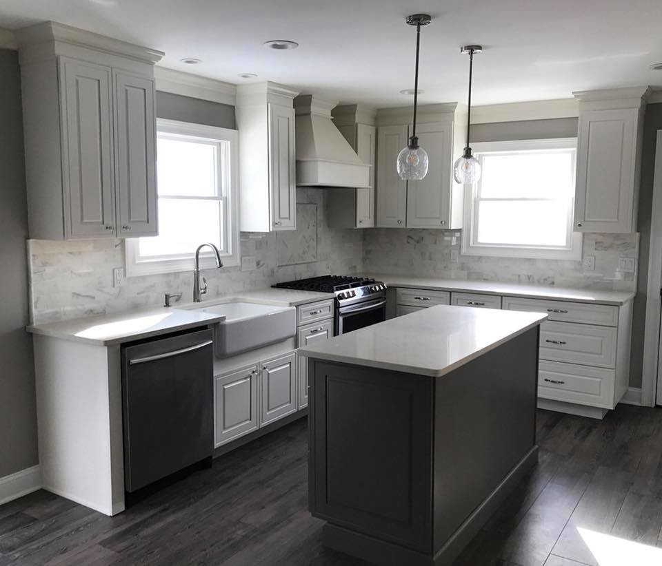 Photo of a small transitional l-shaped eat-in kitchen in Miami with a farmhouse sink, raised-panel cabinets, yellow cabinets, quartzite benchtops, multi-coloured splashback, marble splashback, stainless steel appliances, medium hardwood floors, with island, grey floor and white benchtop.