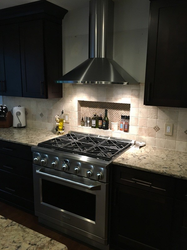 Example of a large transitional u-shaped porcelain tile open concept kitchen design in Detroit with a farmhouse sink, shaker cabinets, white cabinets, quartz countertops, beige backsplash, stone tile backsplash, stainless steel appliances and an island