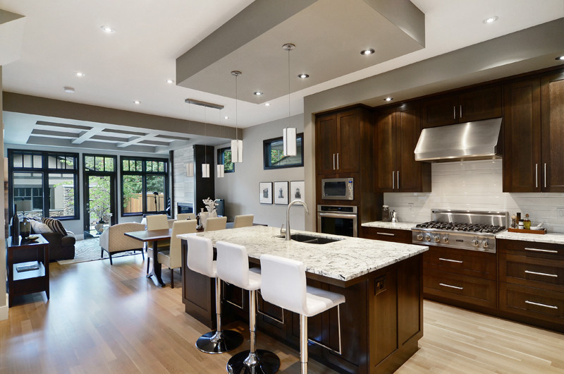 Open concept kitchen - large transitional l-shaped vinyl floor open concept kitchen idea in Calgary with a double-bowl sink, shaker cabinets, dark wood cabinets, marble countertops, white backsplash, subway tile backsplash, stainless steel appliances and an island