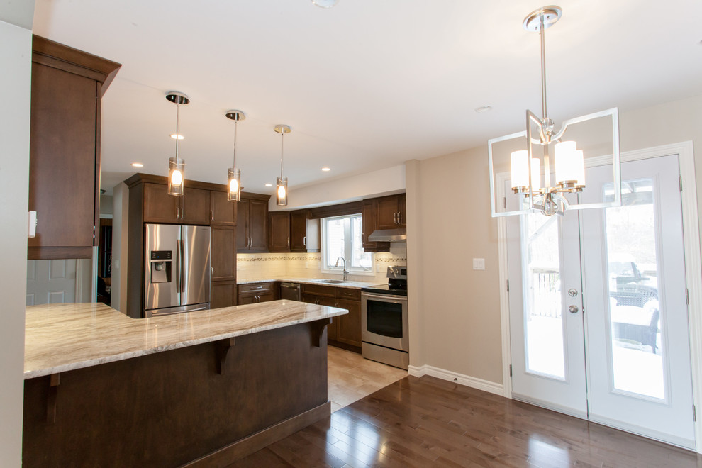 Example of a mid-sized transitional u-shaped porcelain tile eat-in kitchen design in Toronto with an undermount sink, recessed-panel cabinets, dark wood cabinets, granite countertops, white backsplash, porcelain backsplash, stainless steel appliances and a peninsula